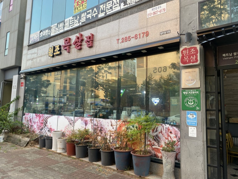 원조목살집 간판과 유리창 앞 화분들.
