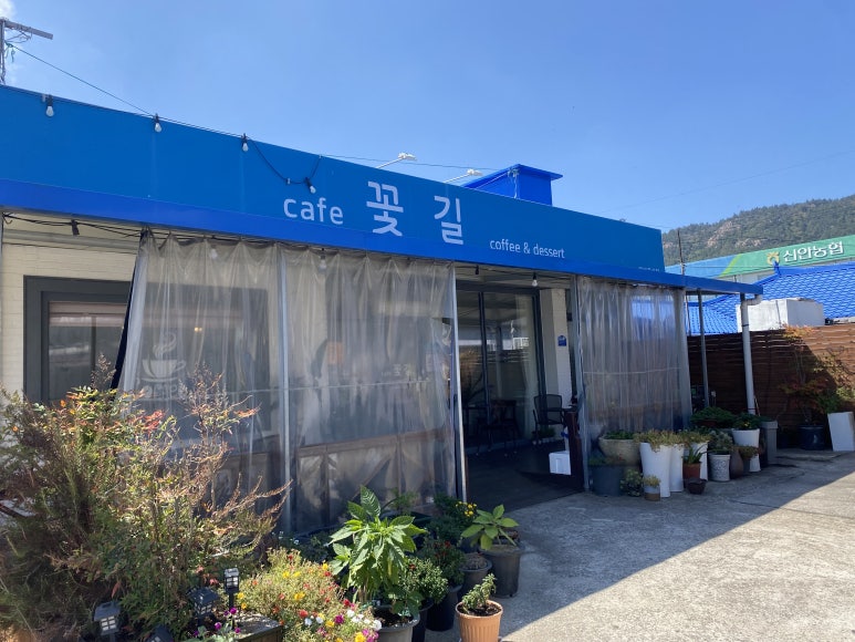 파란 간판과 화분이 있는 카페꽃길 외관